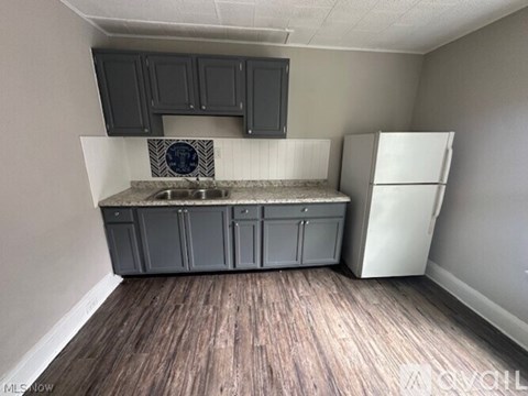 A kitchen with a white fridge and a sink with a black and white tile backsplash.
