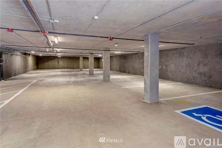 A spacious parking garage with a blue handicap sign on the floor.