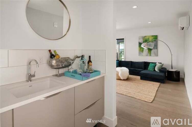 A modern kitchen with a white sink and a round mirror above it.