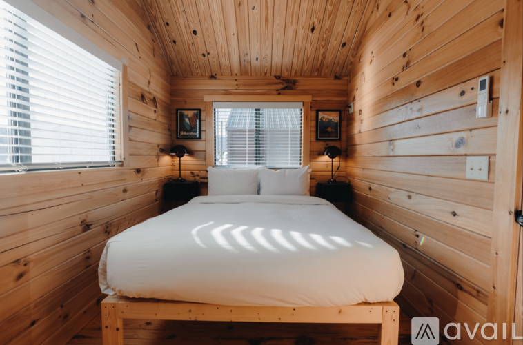A bed in a wooden room with a window.