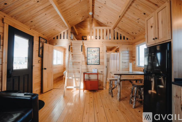 A wooden cabin with a black fridge and a table with chairs.
