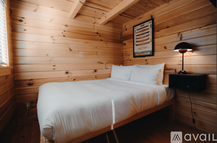 A bedroom with a bed, lamp, and picture on the wall.