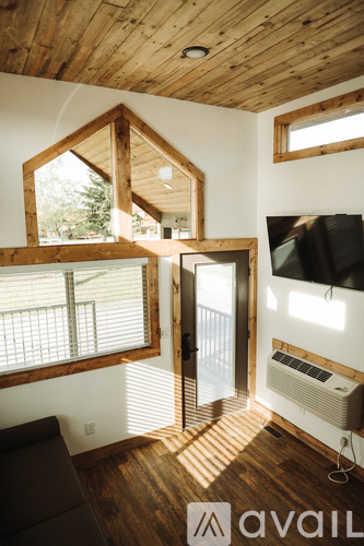 A living room with a wooden ceiling and a television mounted on the wall.