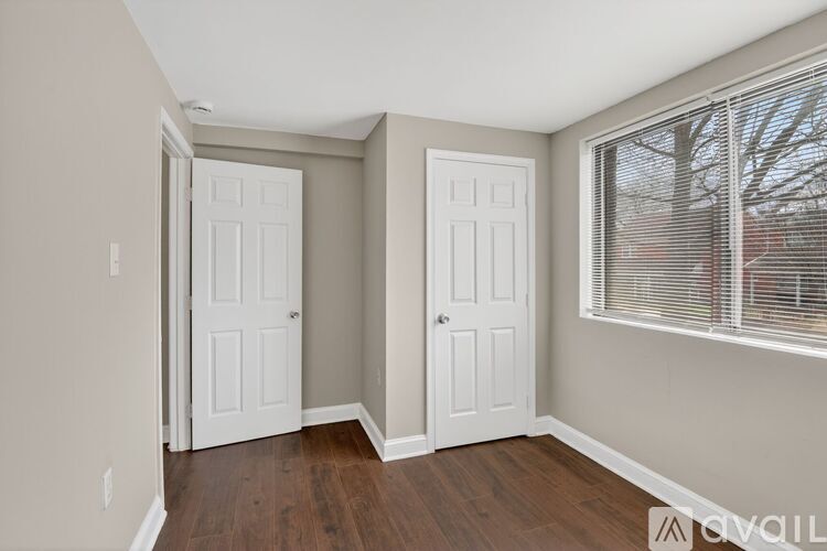 A room with two white doors and a window with blinds.
