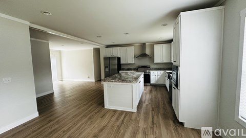 A kitchen with white cabinets and a wooden floor.