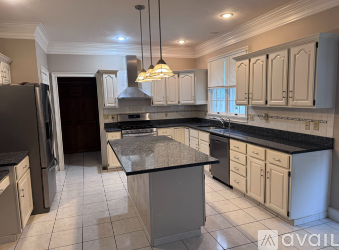 A kitchen with a black granite countertop and white cabinets.