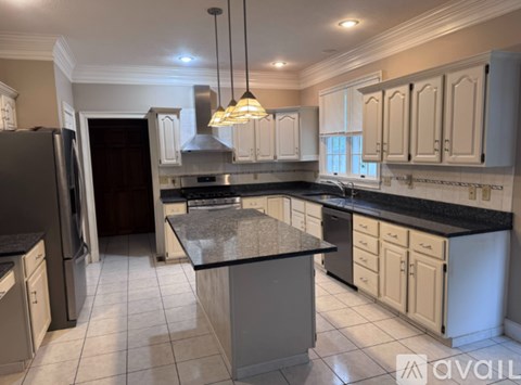 A kitchen with a black granite countertop and white cabinets.