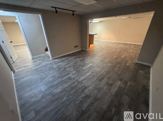 A spacious room with wooden flooring and a bar area.
