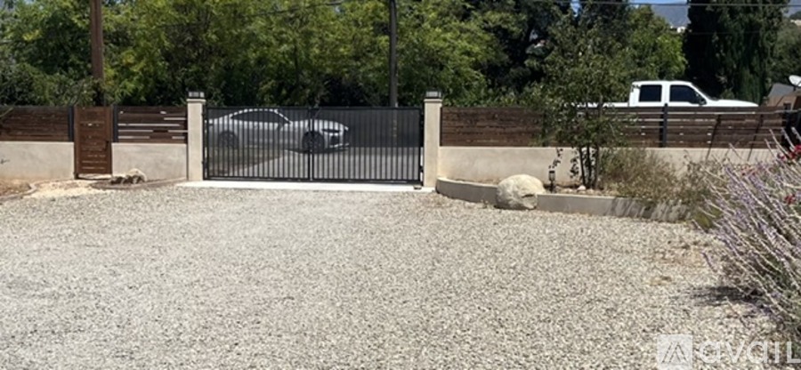 A black gate is in front of a white car.
