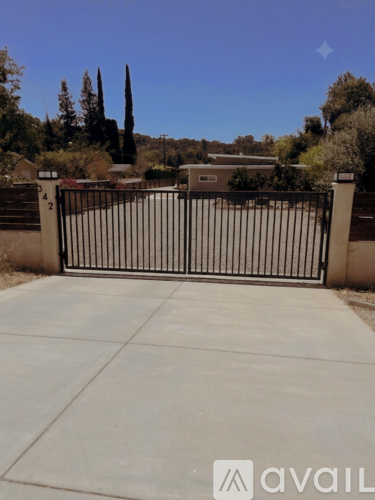 A black gate with a white sign that says "avail" in front of a house.