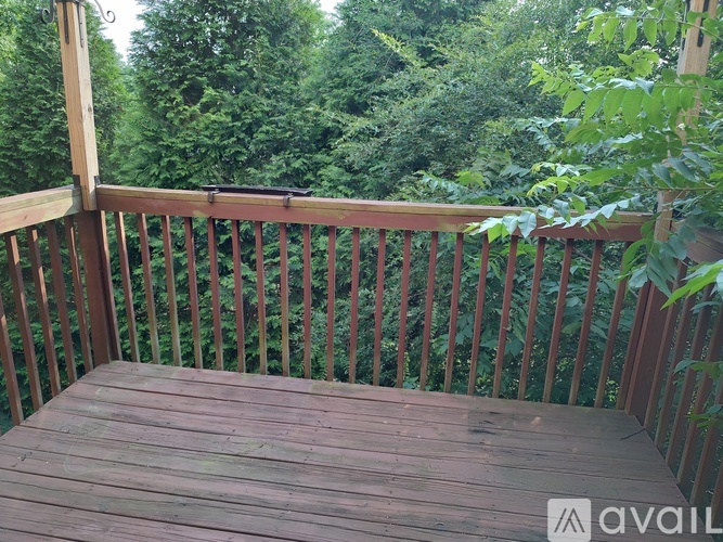 A wooden deck with a railing and trees in the background.