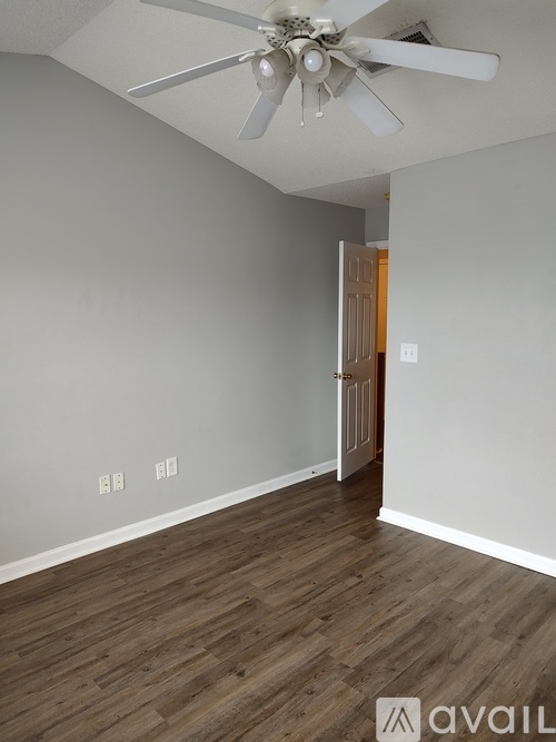 A room with a ceiling fan and wooden flooring.