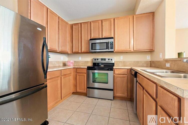 A kitchen with wooden cabinets and a stainless steel refrigerator.