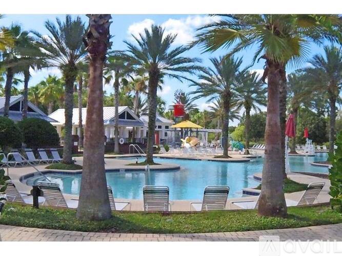 A pool surrounded by palm trees and lounge chairs.