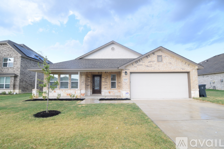 A house with a garage and a tree in front.