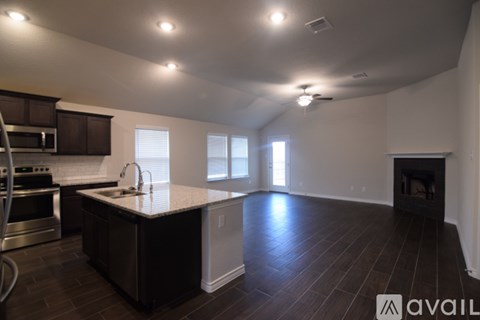 A kitchen with dark wood floors and a large island in the middle.