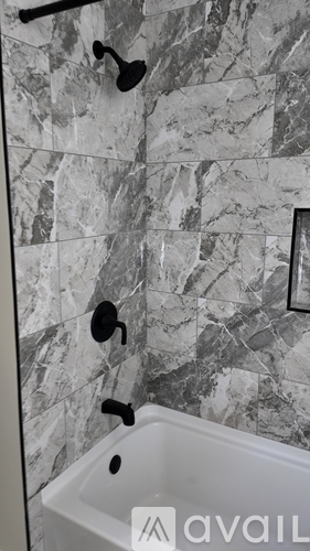 A bathroom with a marble tile wall and a white bathtub.