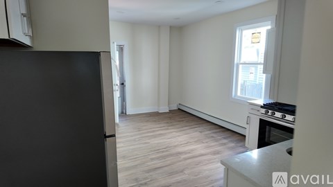 A kitchen with a black refrigerator and a window with a view of a building outside.