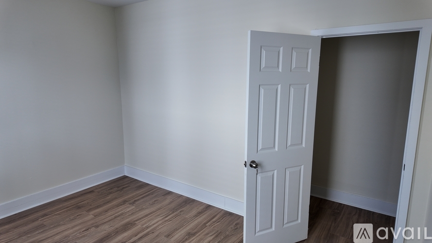 A room with a white door and wooden flooring.
