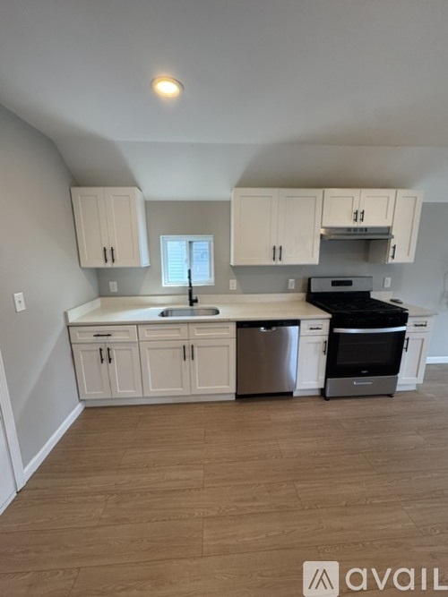 A kitchen with white cabinets and a wooden floor.