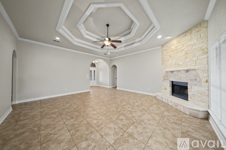 A spacious room with a fireplace and a fan on the ceiling.