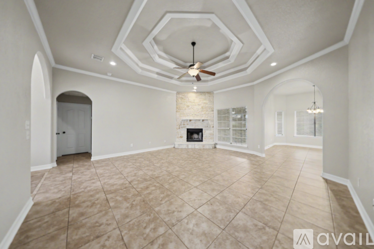 A spacious living room with a fireplace and a ceiling fan.