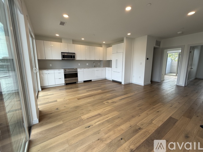 A spacious kitchen with wooden flooring and white cabinets.
