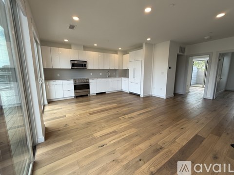 A spacious kitchen with wooden flooring and white cabinets.