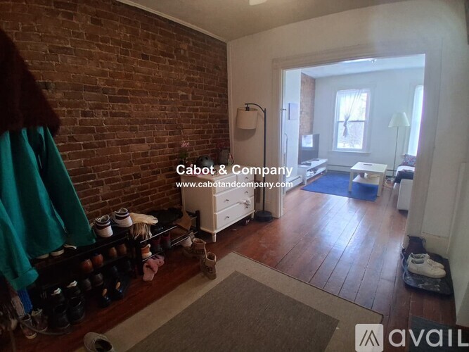 A room with a brick wall and a white dresser.