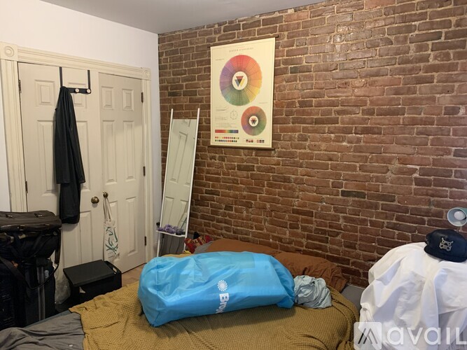 A bedroom with a bed, a blue bag, and a poster on the wall.