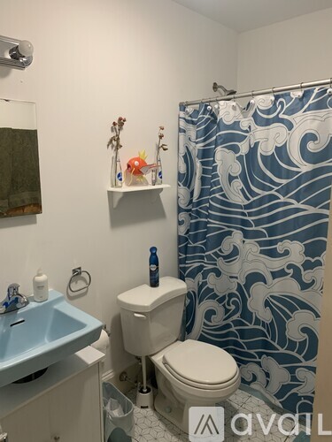 A bathroom with a blue shower curtain and a white toilet.