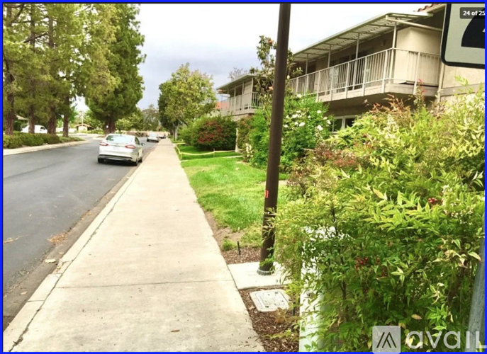 A street view with a car driving down the road and a building on the right.