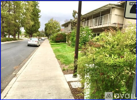 A street view with a car driving down the road and a building on the right.