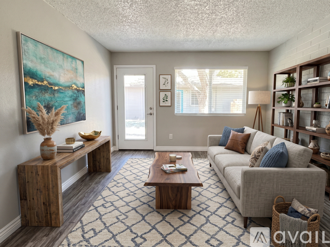 A living room with a grey couch, a wooden table, and a painting on the wall.