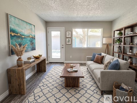A living room with a grey couch, a wooden table, and a painting on the wall.