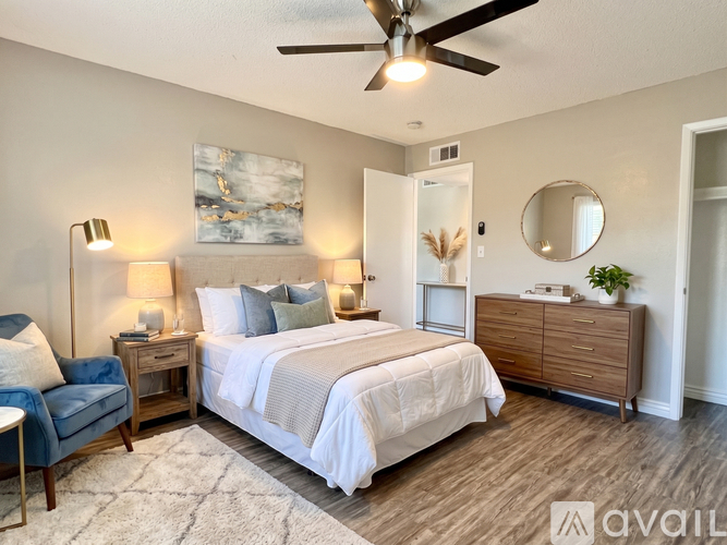 A bedroom with a bed, a chair, a dresser, and a ceiling fan.