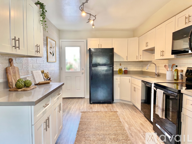 A kitchen with a black refrigerator and white cabinets.