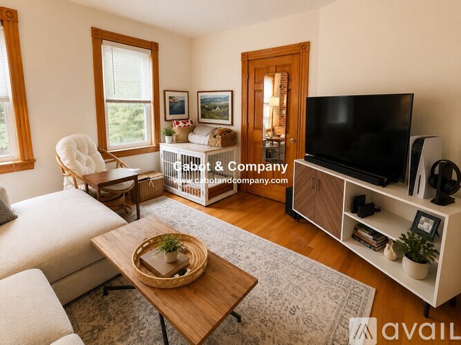 A living room with a white couch, a wooden coffee table, and a television on a stand.
