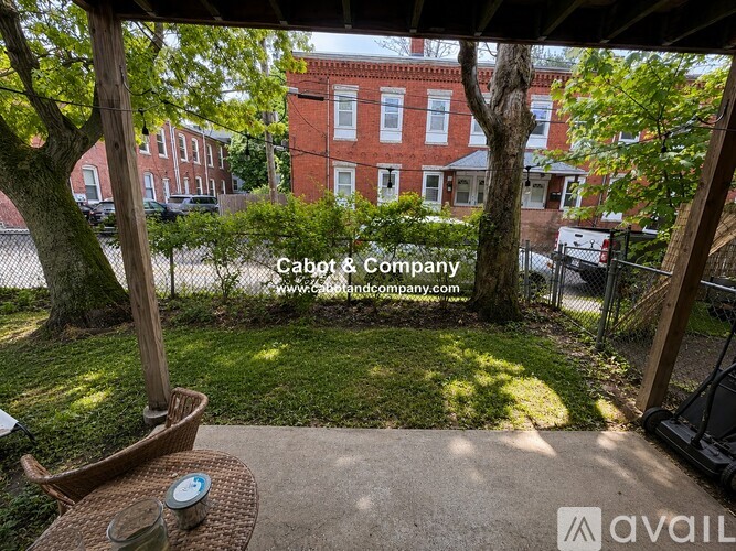 A patio with a table and chairs overlooking a grassy area and a red brick building.