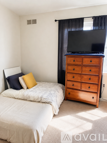 A bedroom with a bed, dresser, and television.
