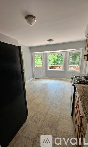 A kitchen with a black fridge and a window with a view of a garden.