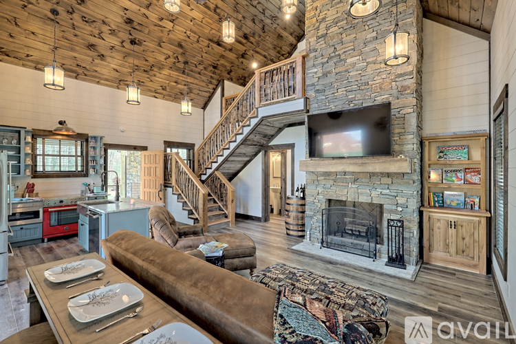 A living room with a stone fireplace and a television mounted above it.