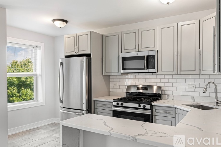 A kitchen with a refrigerator, microwave, oven, and sink.