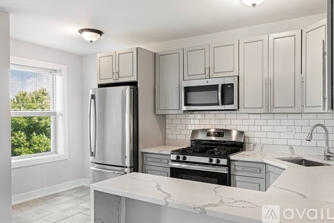 A kitchen with a refrigerator, microwave, oven, and sink.
