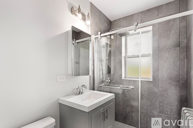 A bathroom with a white sink and grey tiled walls.