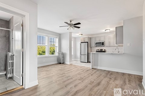 A spacious kitchen and living room with a ceiling fan and lighting fixtures.