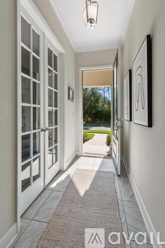 A hallway with a rug on the floor and pictures on the wall.