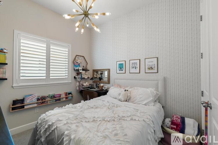 A bedroom with a white bed and a chandelier.