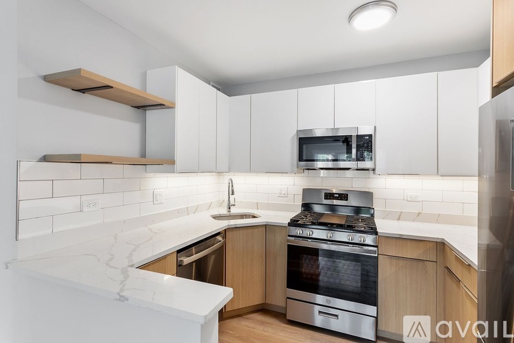 A modern kitchen with a white marble countertop and stainless steel appliances.