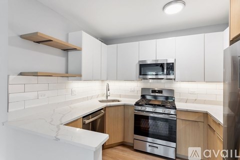 A modern kitchen with a white marble countertop and stainless steel appliances.